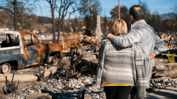couple hugging in front of burned land